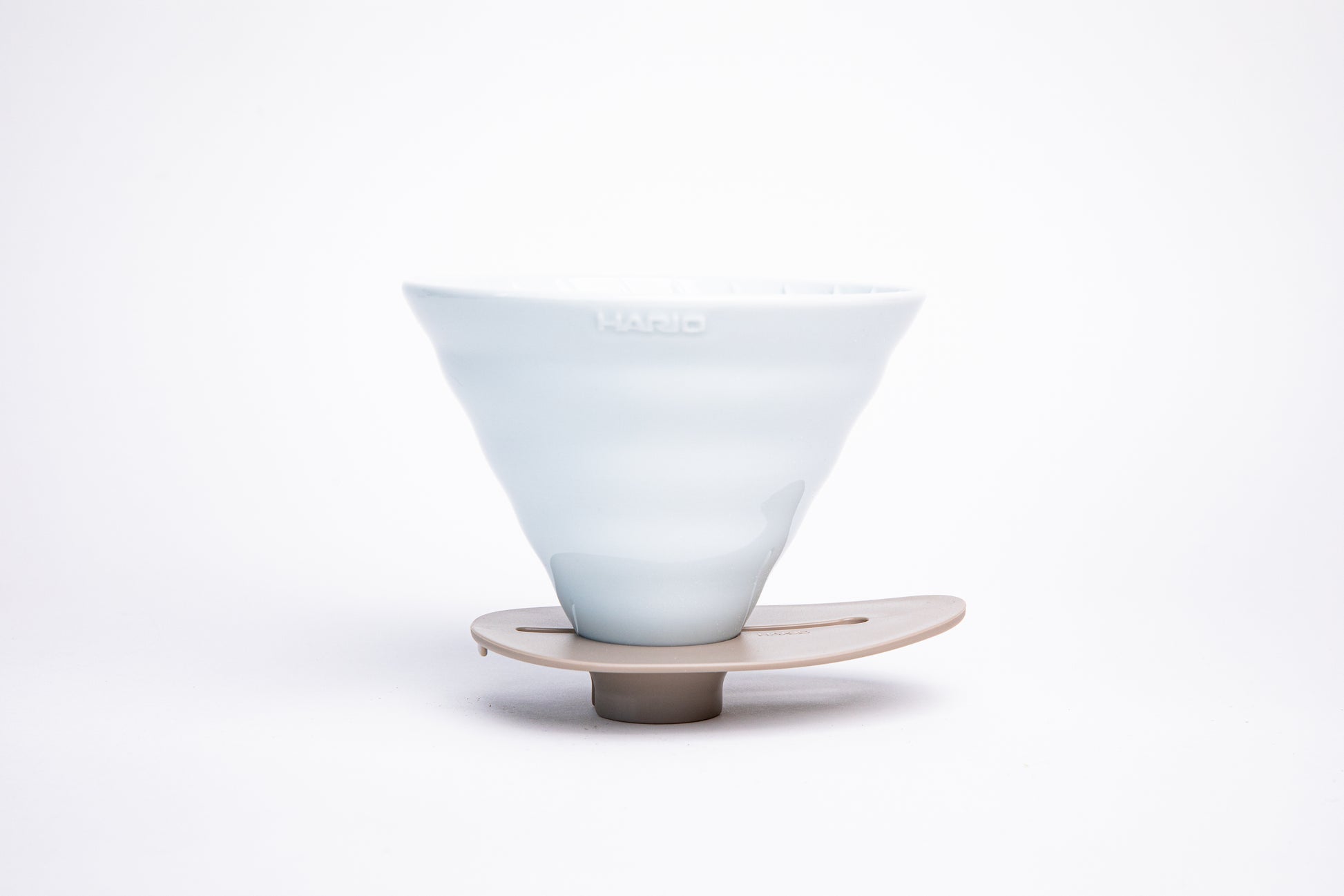 white ceramic cone dripper on a ivory base on a white background
