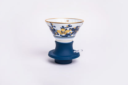 white cone dripper with a blue and white design on a blue silicone base on white background.