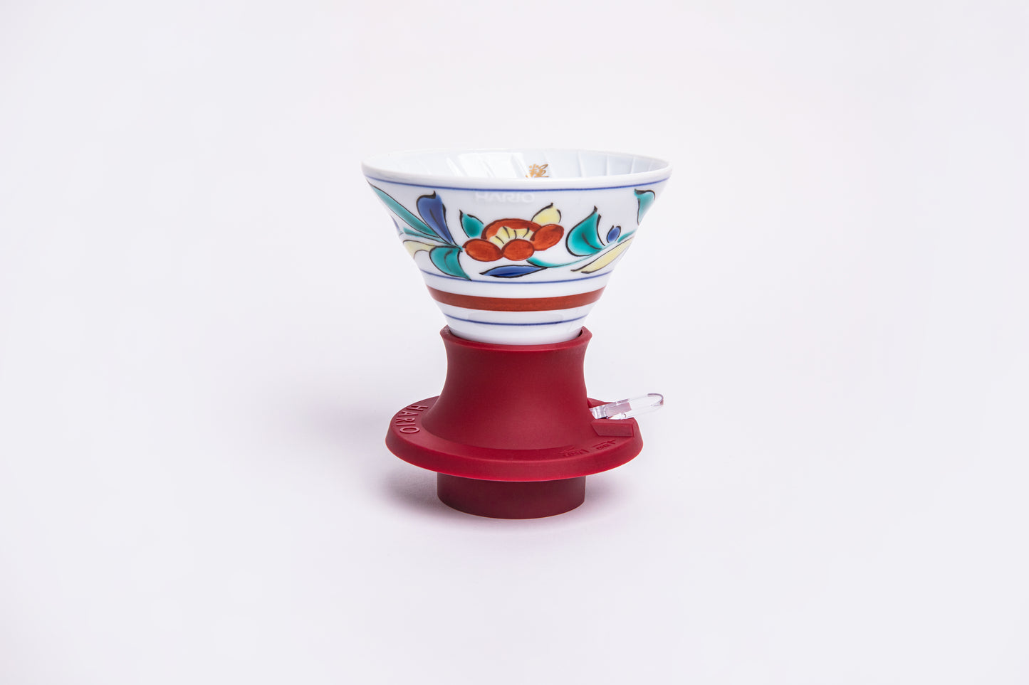 white cone dripper with floral design on a red silicone base on white background.