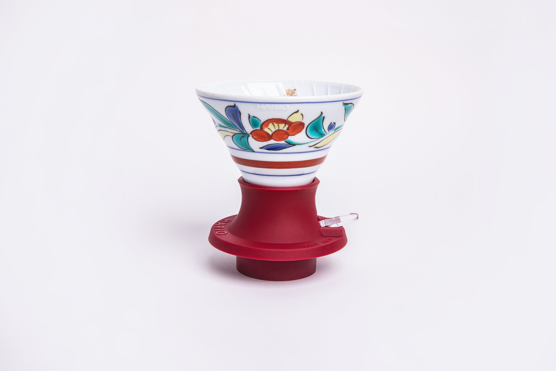white cone dripper with floral design on a red silicone base on white background.