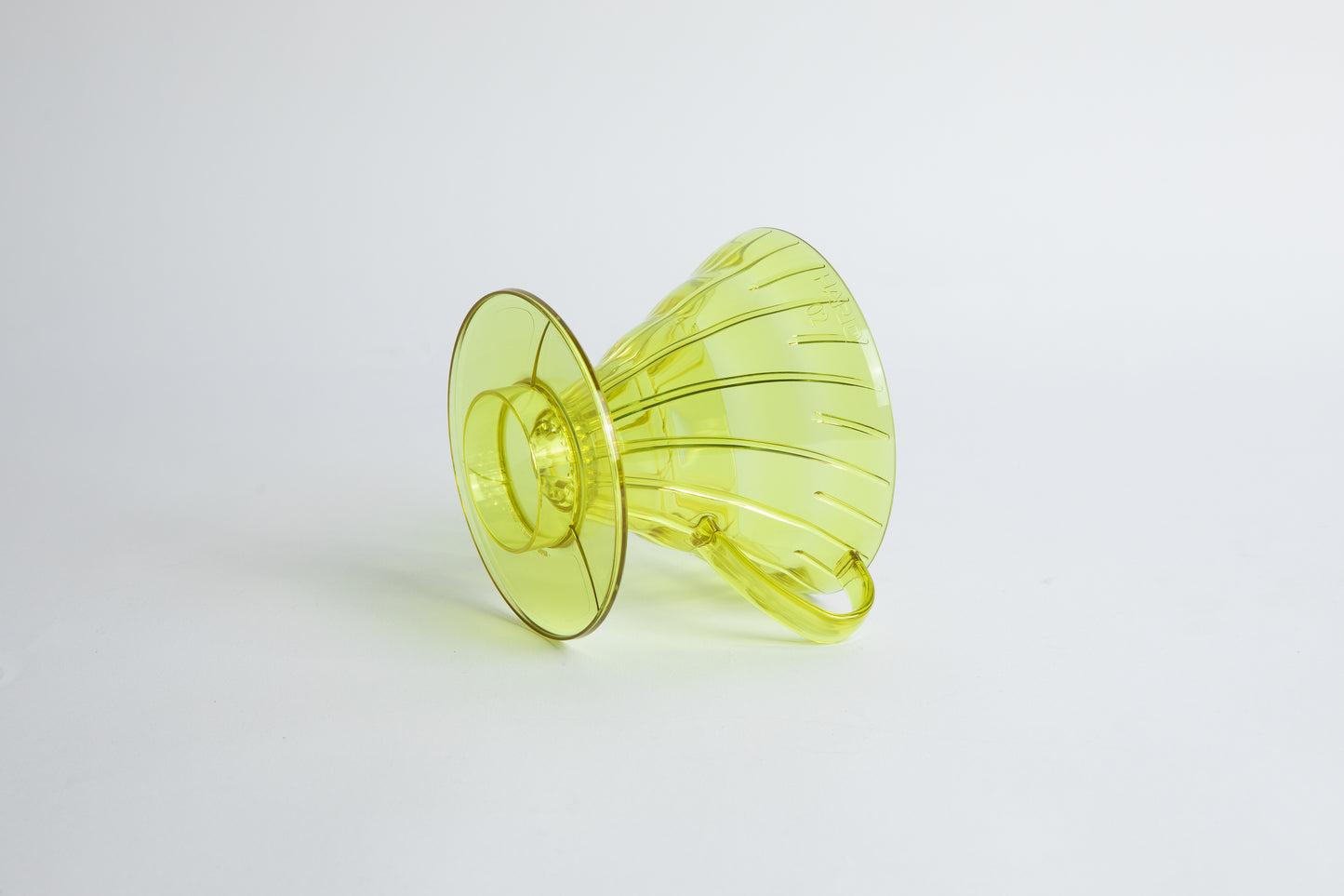 set on it's side the Size 02 Plastic V60 Dripper in the color transparent Chartreuse (Aurora) with a cylindrical base and curved handle. Set on a white background