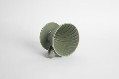 &quot;Oil Green&quot; sage colored 60 degree cone shaped ceramic coffee dripper with handle and round base. Spiral ribbed on the inside cone. Set on white background