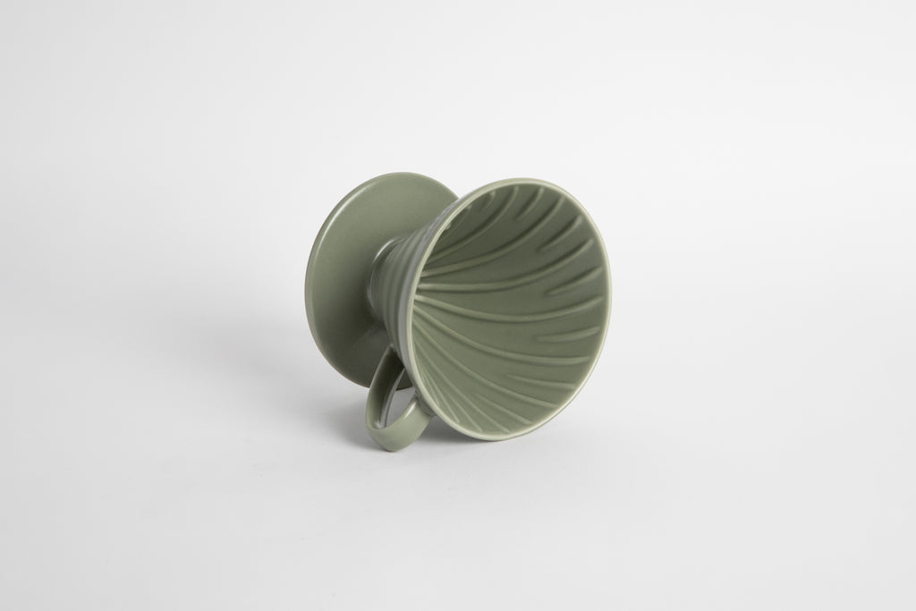 "Oil Green" sage colored 60 degree cone shaped ceramic coffee dripper with handle and round base. Spiral ribbed on the inside cone. Set on white background
