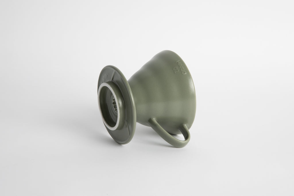 "Oil Green" sage colored 60 degree cone shaped ceramic coffee dripper with handle and round base. Set on white background