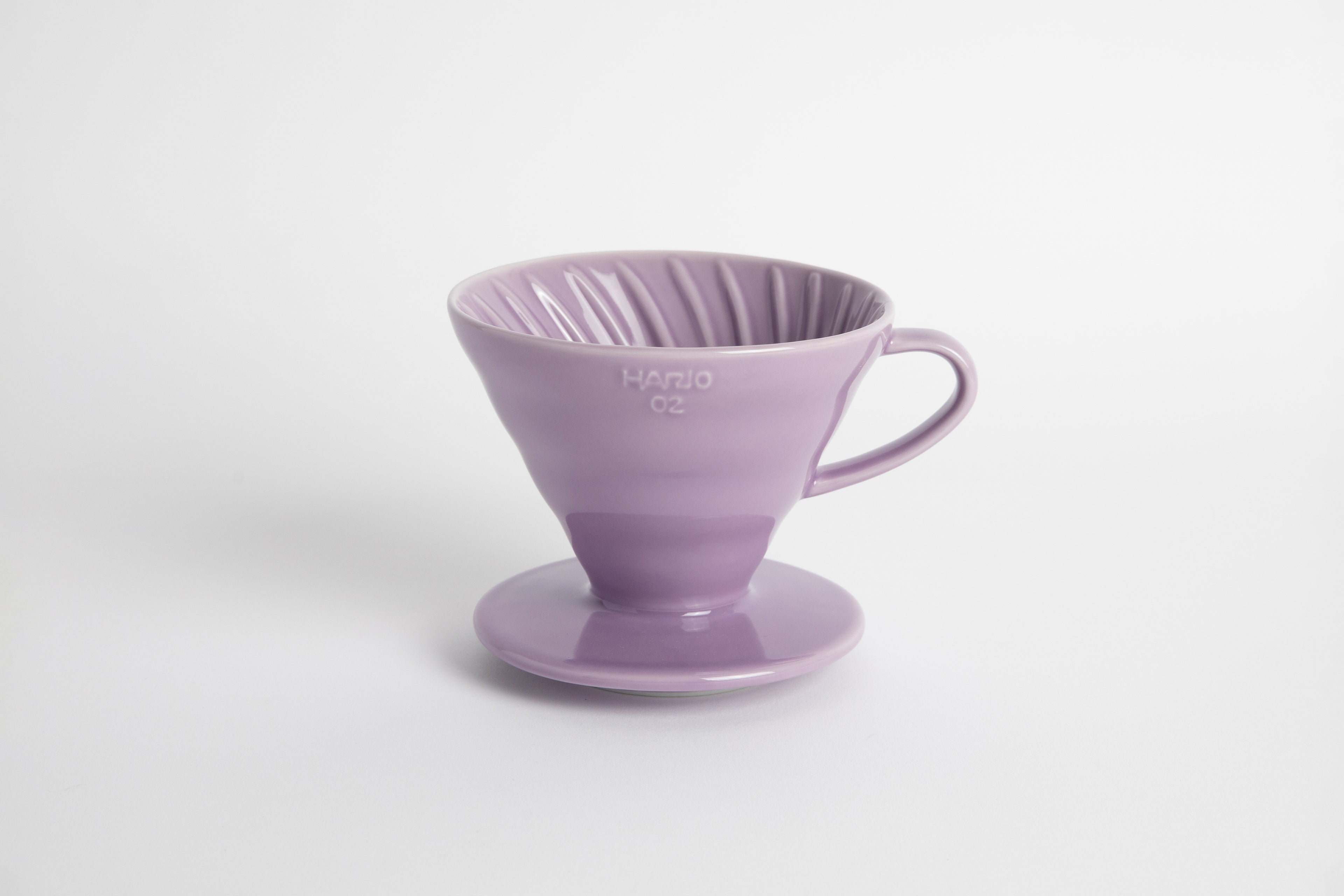 Purple Heather 60 degree cone shaped ceramic coffee dripper with handle and round base. Spiral ribbed on the inside cone. Set on white background