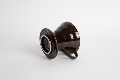 &quot;Saddle&quot; Dark Brown 60 degree cone shaped ceramic coffee dripper with handle and round base. Set on white background