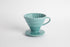 Turquoise 60 degree cone shaped ceramic coffee dripper with handle and round base. Spiral ribbed on the inside cone. Set on white background
