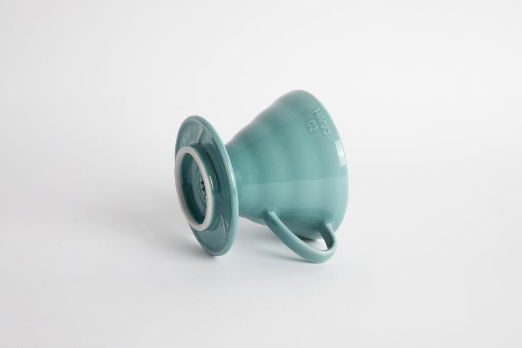 Turquoise 60 degree cone shaped ceramic coffee dripper with handle and round base. Set on white background