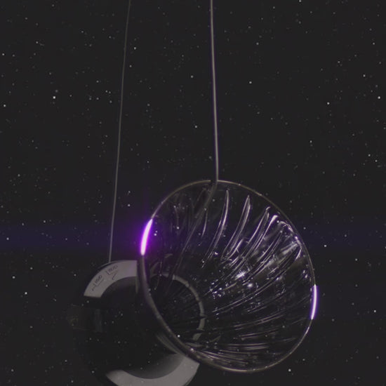 video of hanging cone shape dripper on a silicone black base and small clear plastic trigger floating on starry background.