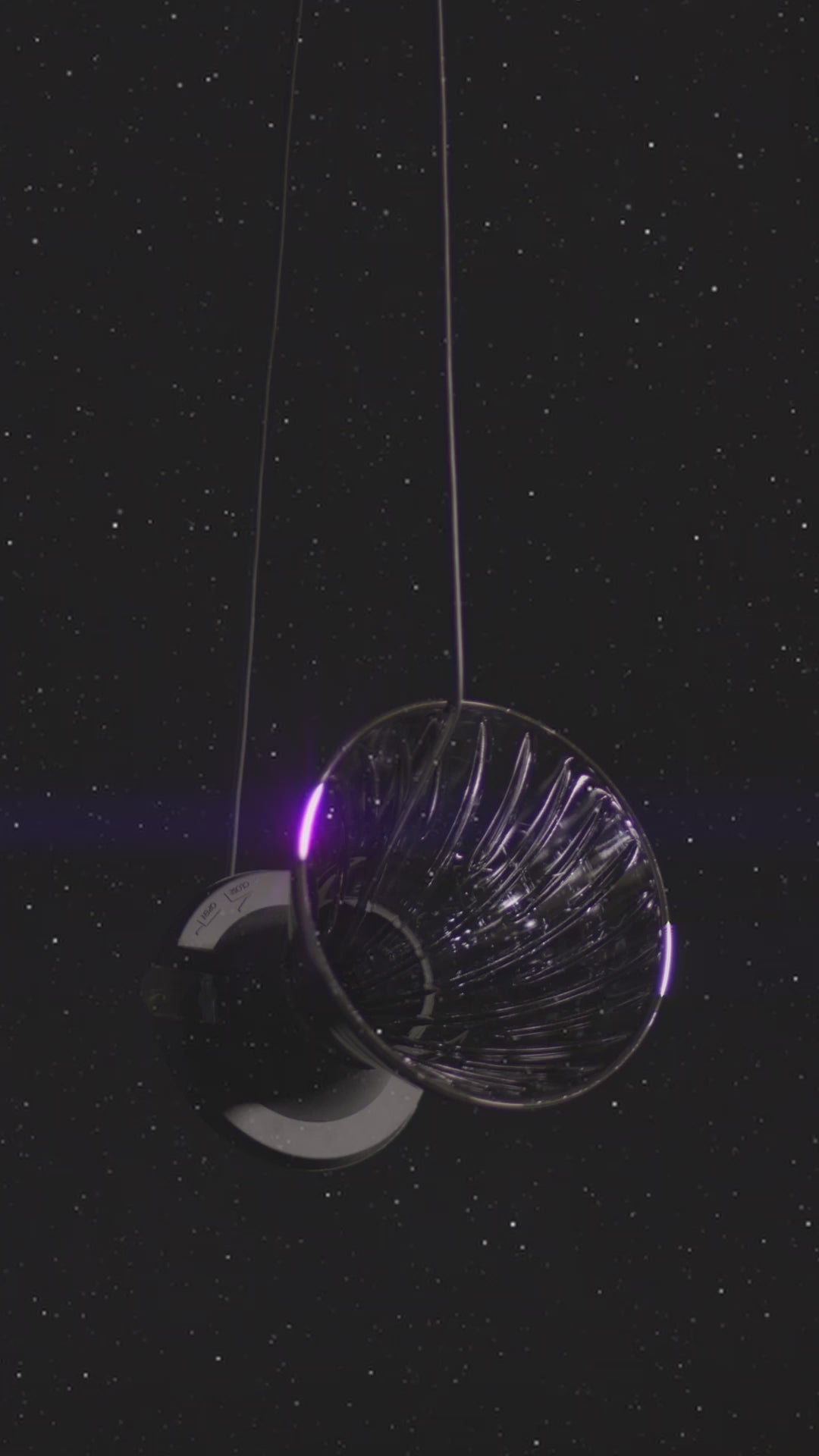 video of hanging cone shape dripper on a silicone black base and small clear plastic trigger floating on starry background.