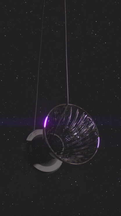 video of hanging cone shape dripper on a silicone black base and small clear plastic trigger floating on starry background.
