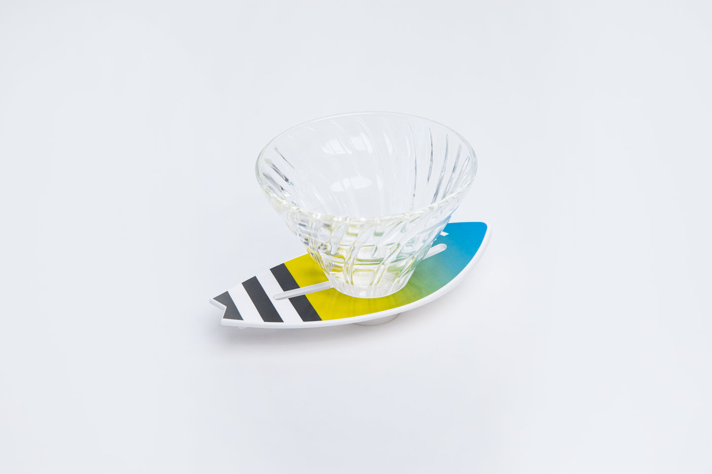 Clear glass v60 dripper on a colorful blue yellow gradient and black striped  surfboard base