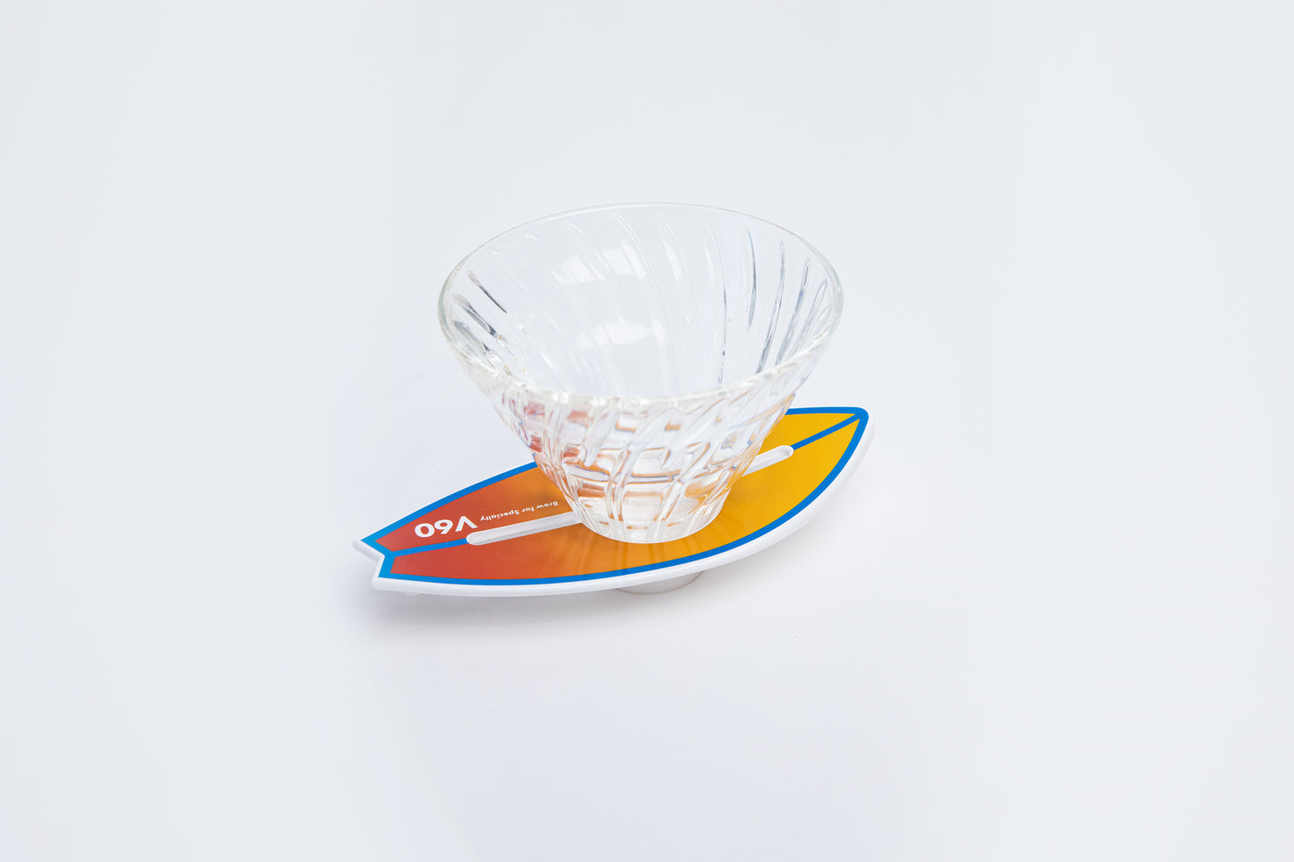 Clear glass v60 dripper on a colorful orange gradient background with v60 brew for specialty and written in white and blue stripe outlining the edge and middle of the surfboard base