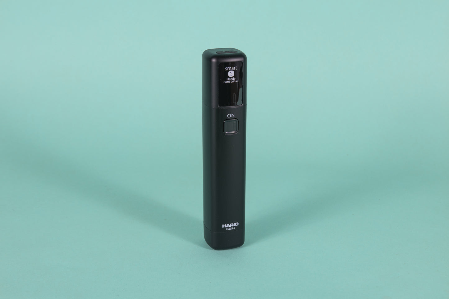 Black monolithic rubberized black plastic device with black screen and a single rounded square button.