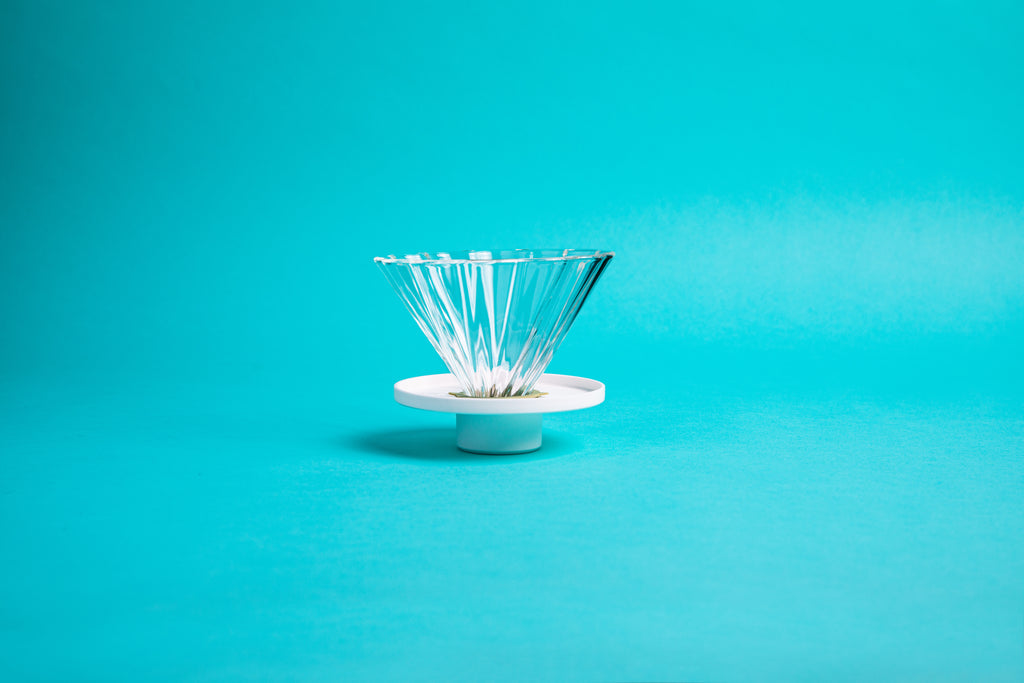 Fluted, flower-shaped glass cone with white plastic base and set against a blue background.