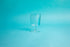 Heatproof square glass goblet with glass stem and foot. Set on blue background.