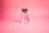 conical glass with a stainless steel cone plug lid and silicone gasket. set on pink background