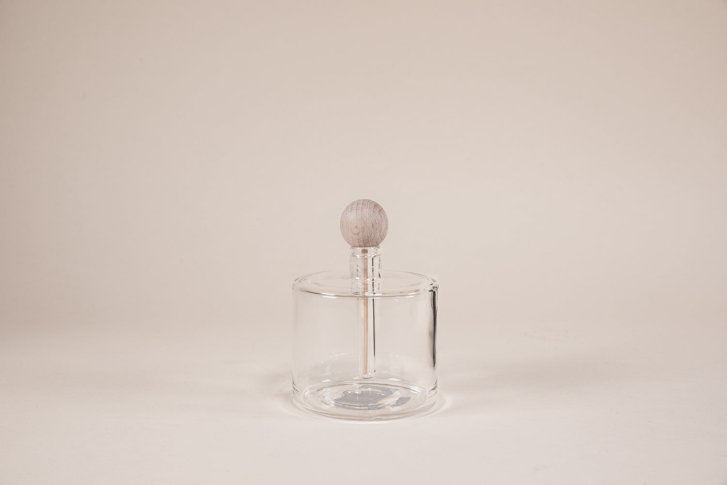 Round glass diffuser with natural wood wand and round knob.