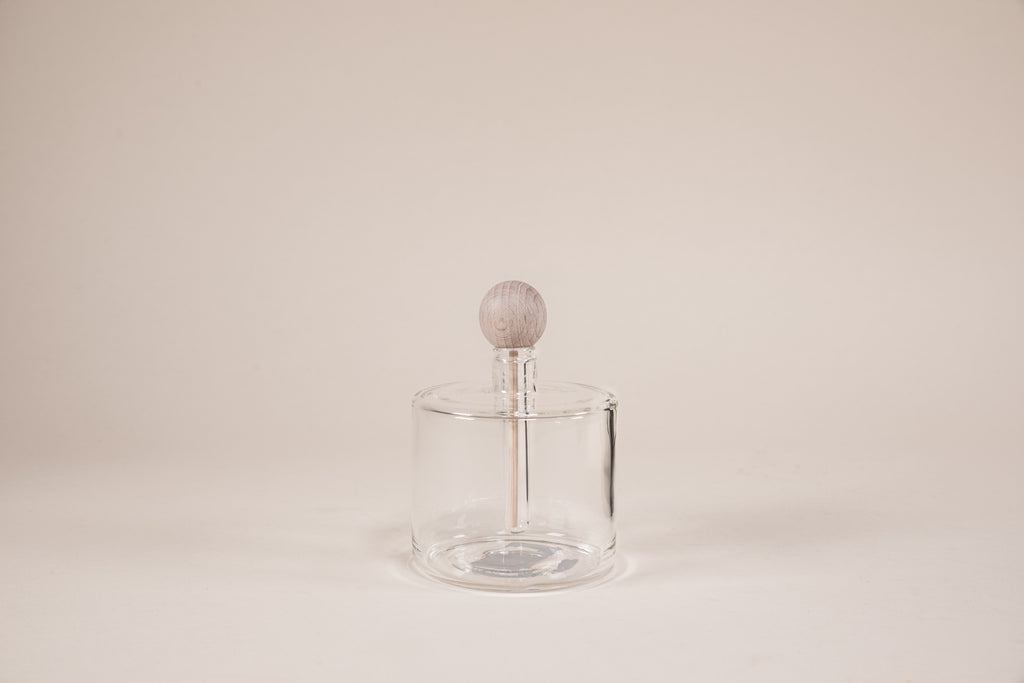 Round glass diffuser with natural wood wand and round knob.