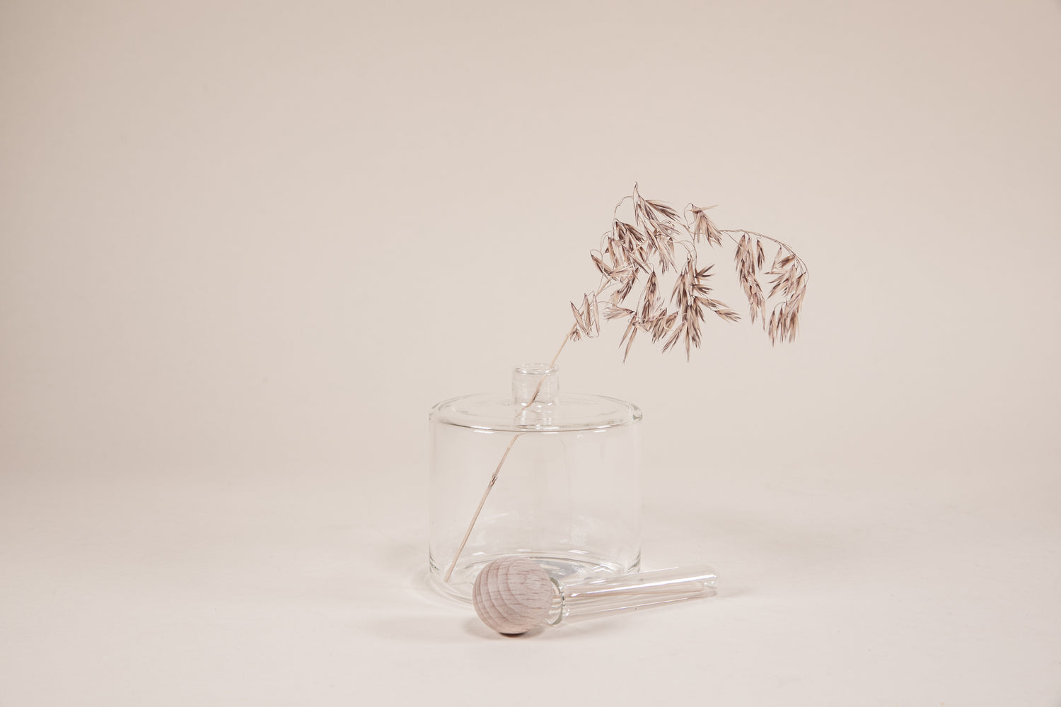 Round glass infuser with plant branch and natural wood wand with round knob.