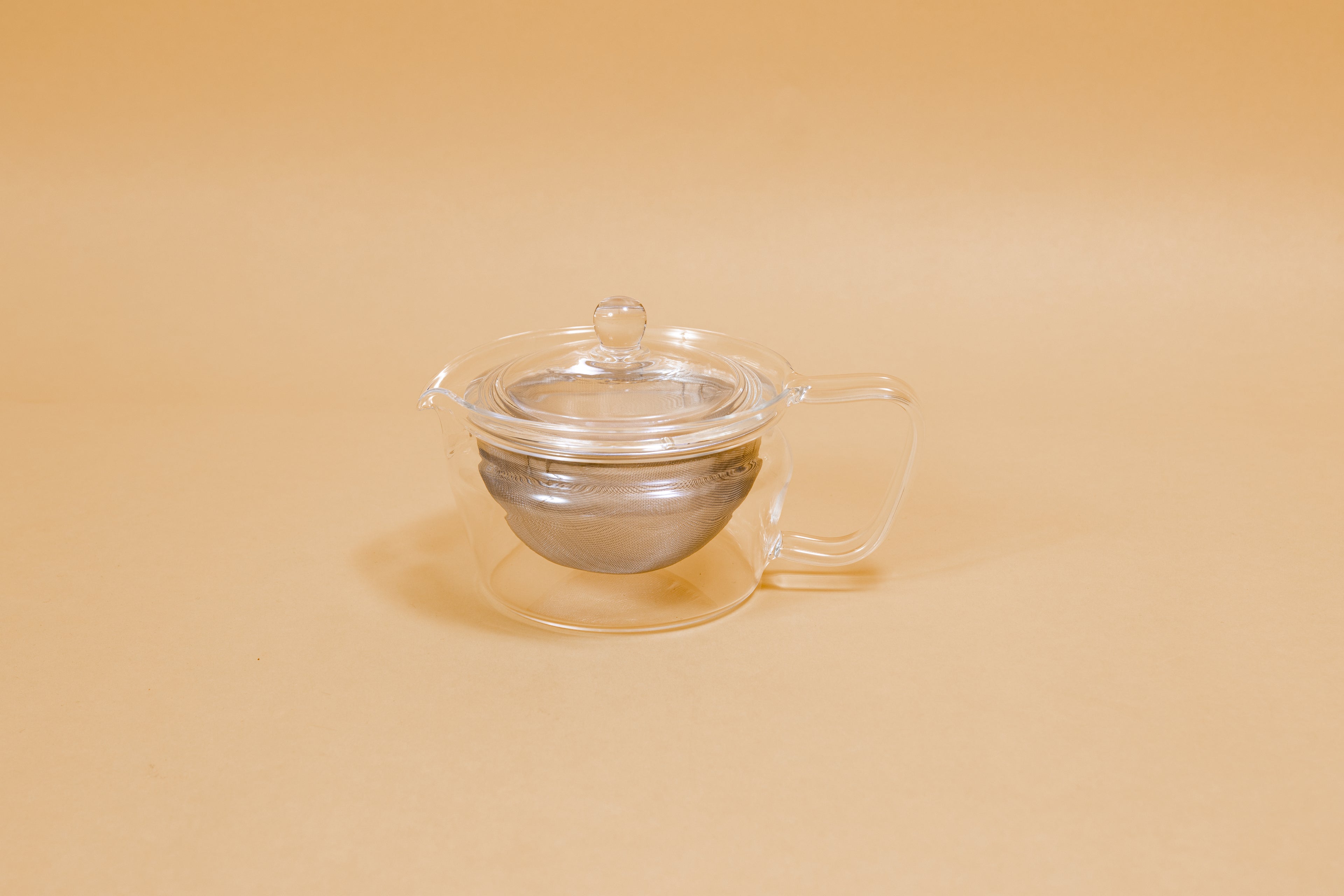 All glass tapered tea pot with flat bottom, all glass lid and handle, and metal mesh filter basket insert.