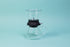 Cylindrical glass tea brewer and metal mesh strainer with clear plastic lid atop a black rubber base with plastic lever sitting on all glass bulbous server