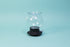 Globulous glass tear brewer and metal mesh filter with clear plastic lid atop a black rubber base with plastic lever switch 