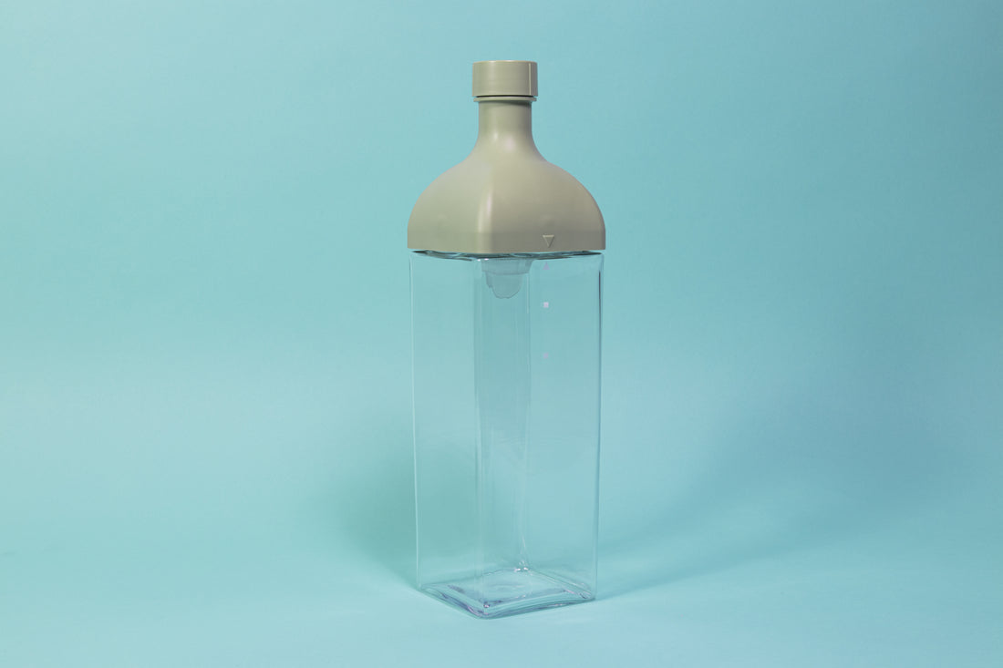 Clear plastic rectangular jug with green rectangular top and round cap.
