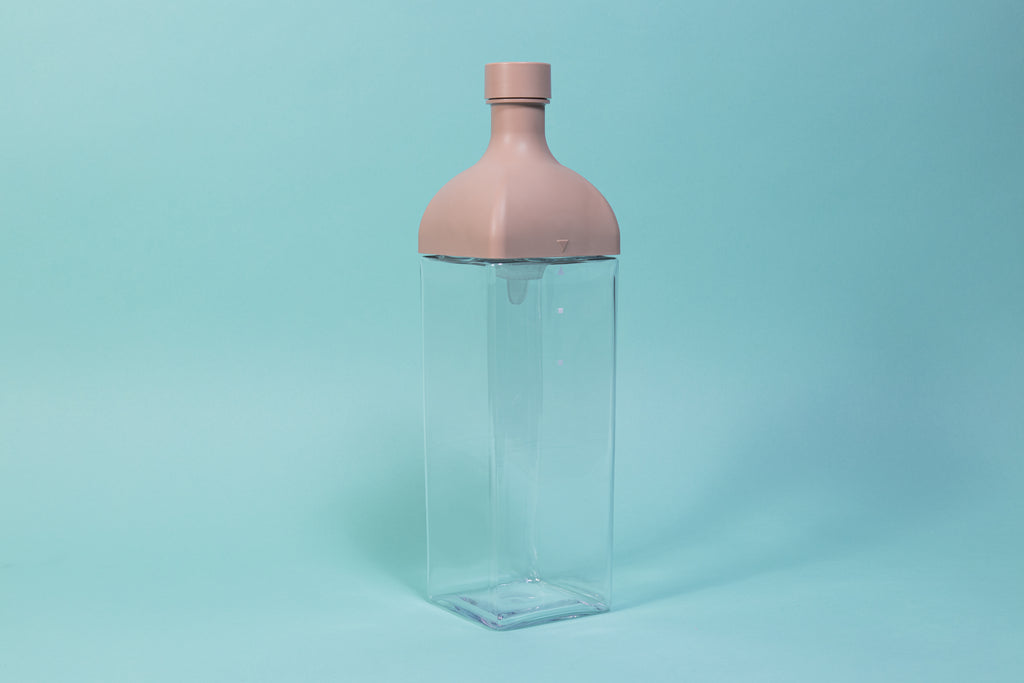 Clear plastic rectangular jug with pink rectangular top and round cap.