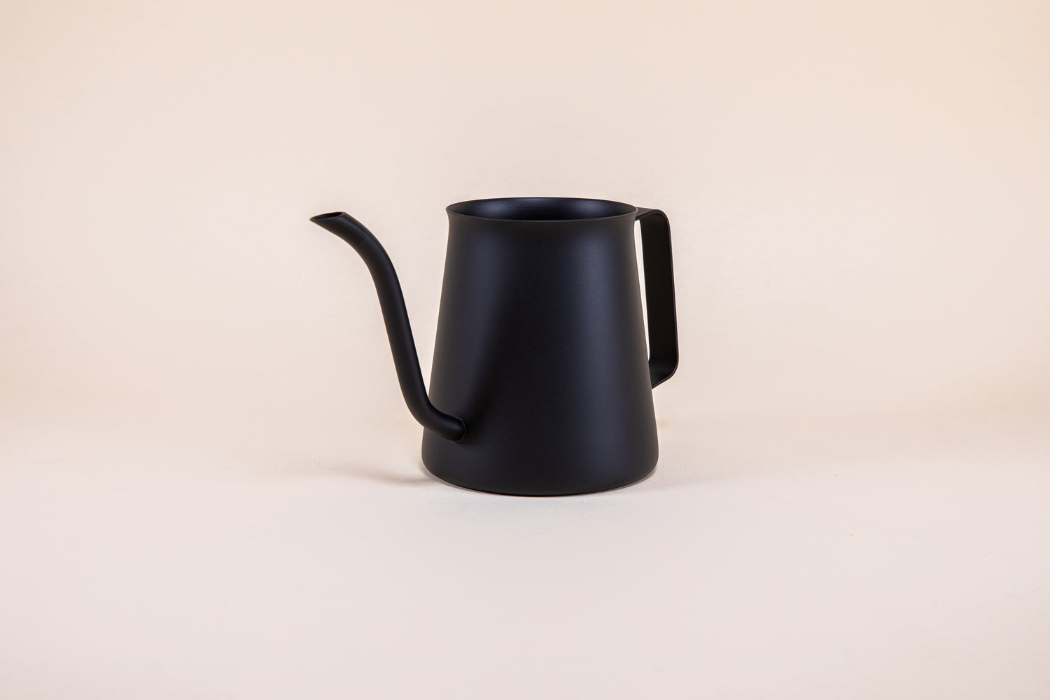 All black metal kettle with flared top, gooseneck spout, and handle on a light background. 