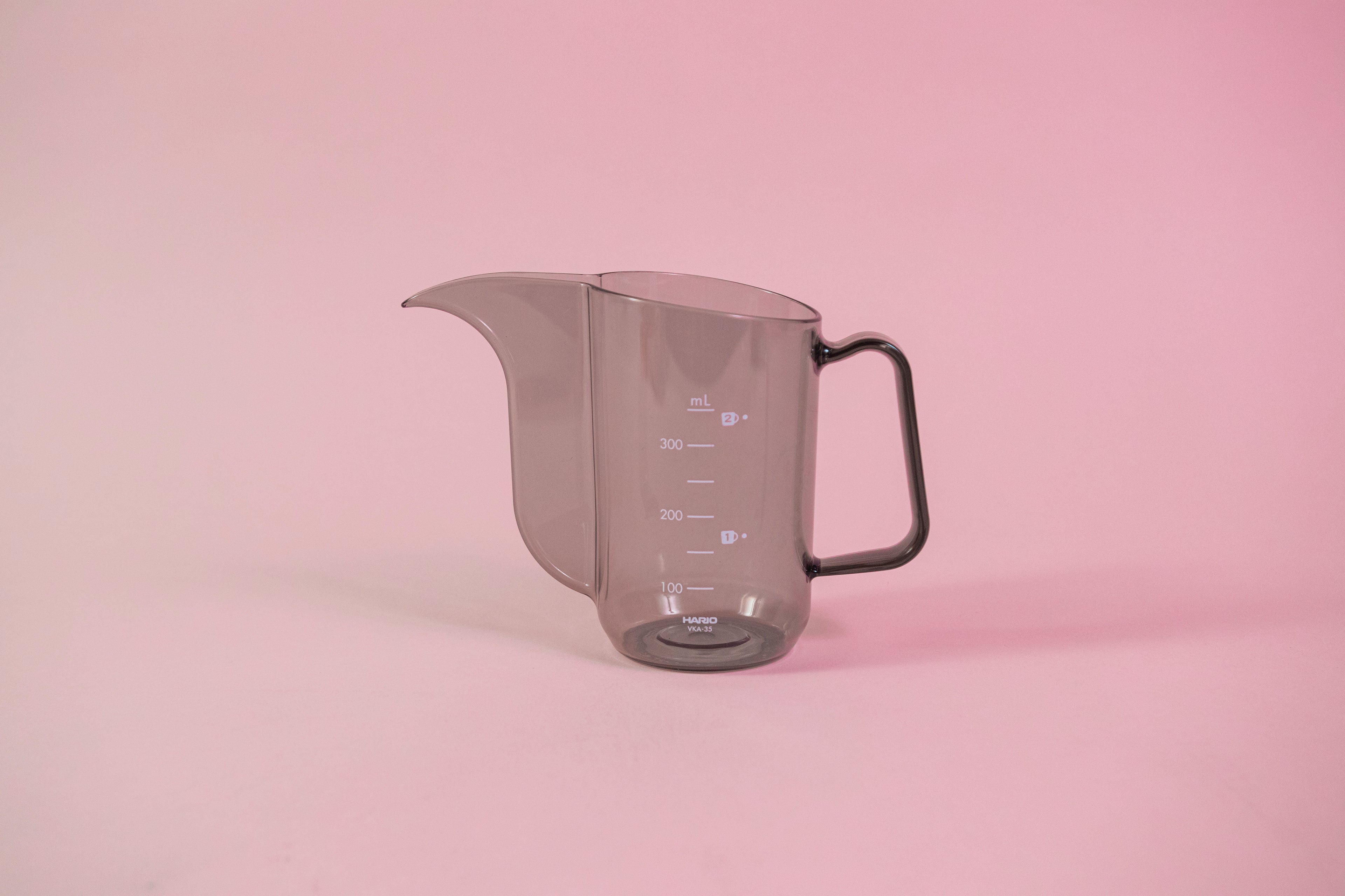 Transparent black plastic cup with handle and gooseneck style pour spout.