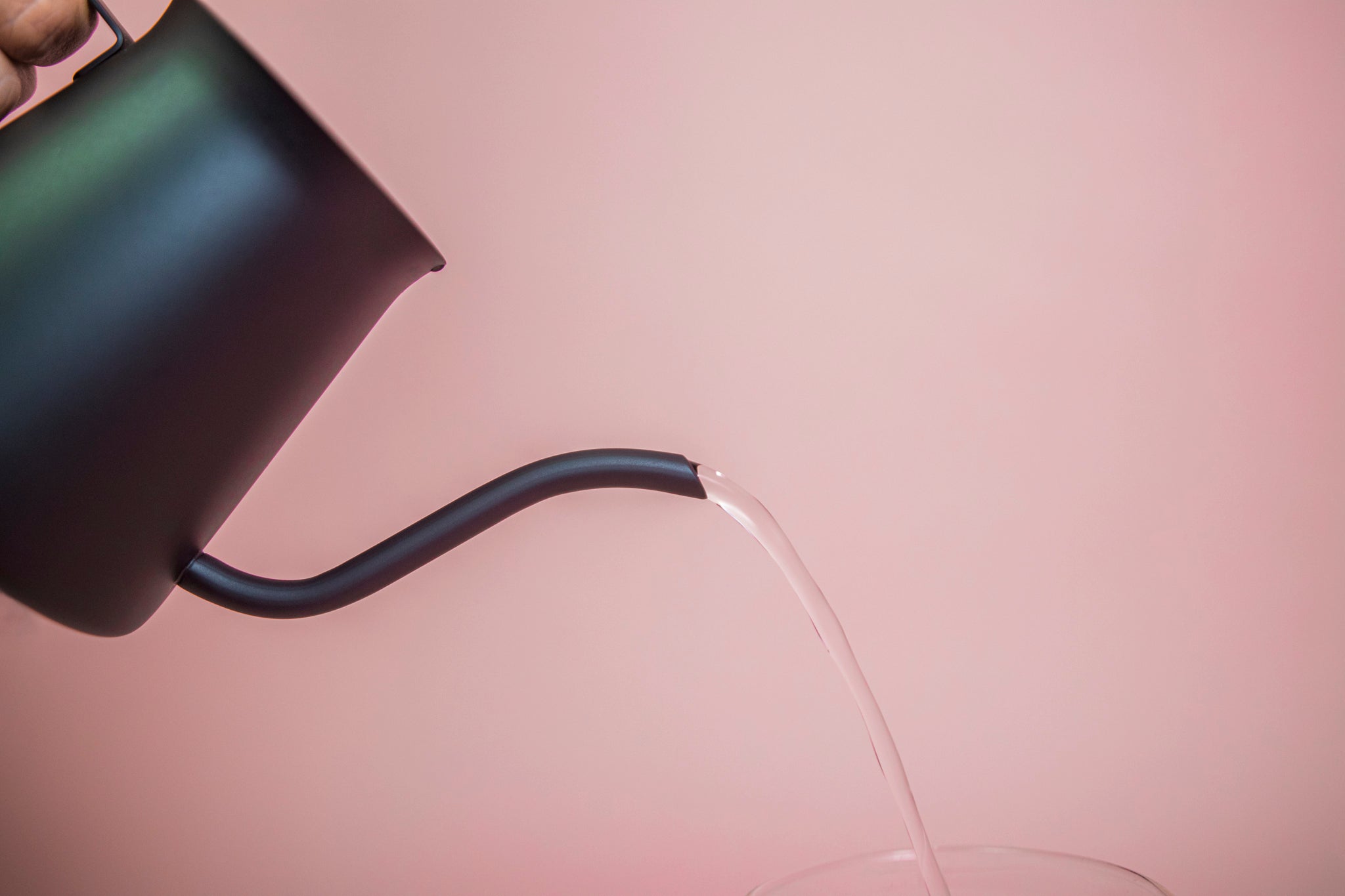 All black metal kettle with flared top, gooseneck, and handle pouring water.