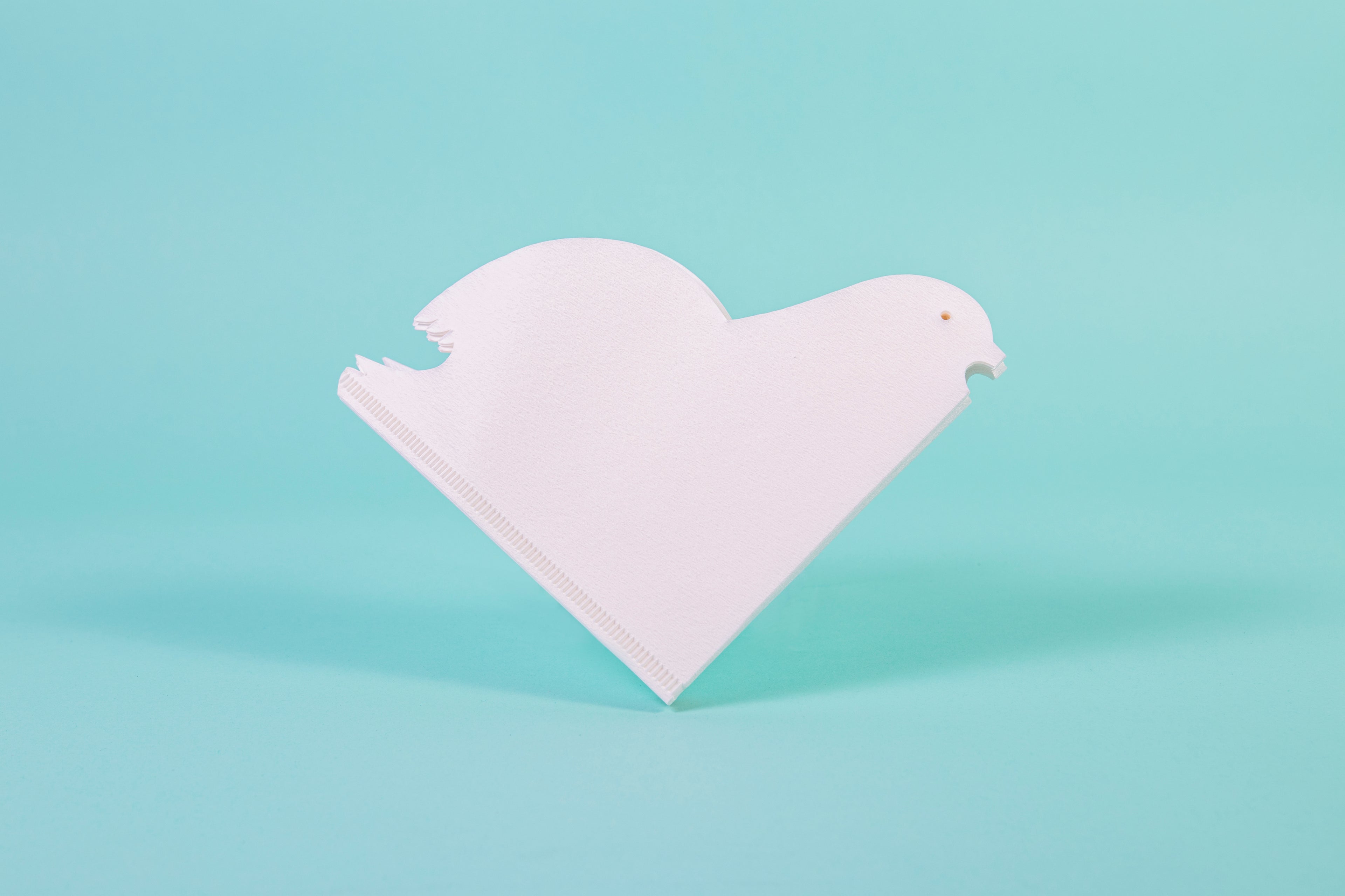 White bird-shaped cone paper filters set against a blue background.