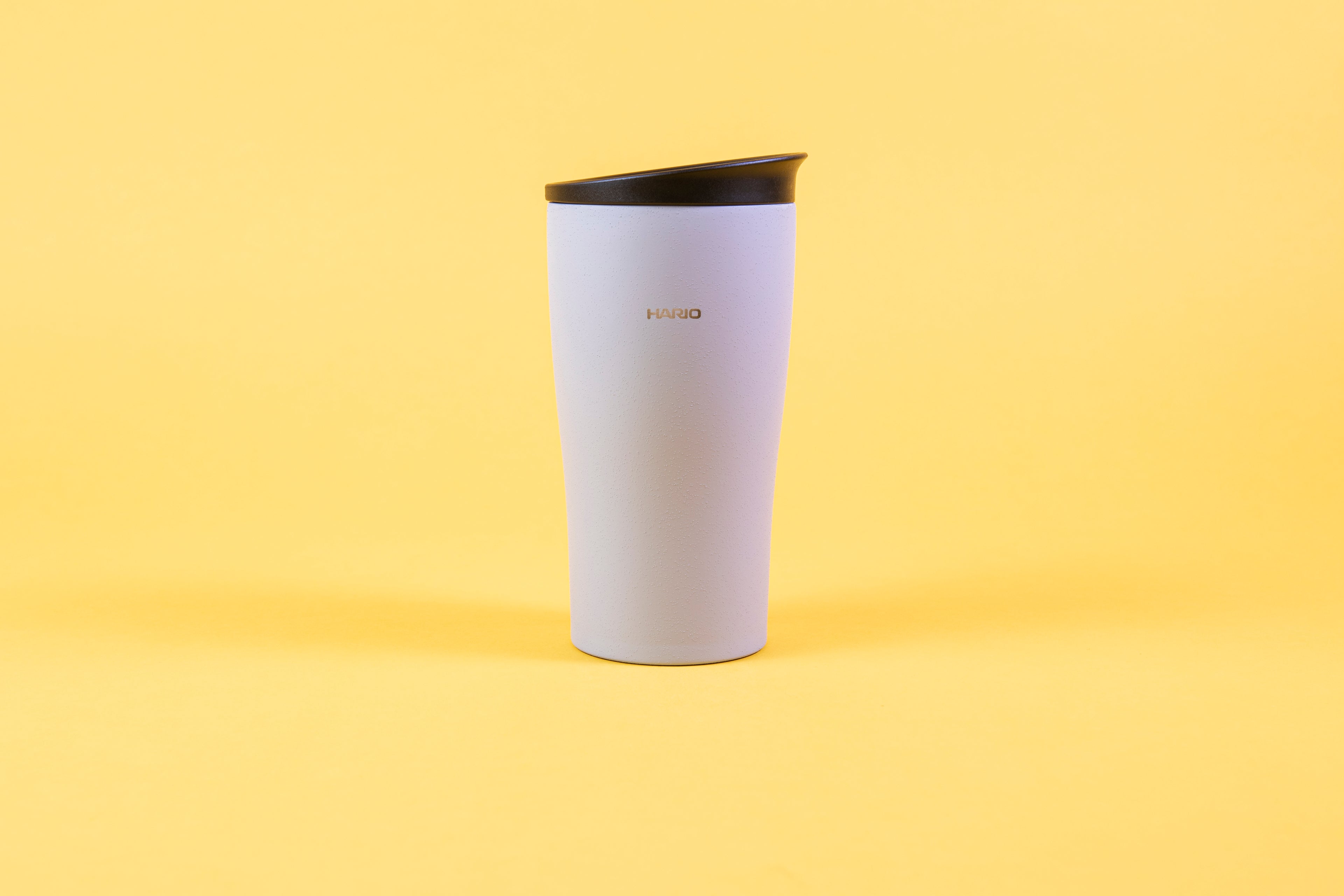 Textured white coffee tumbler with Hario logo and black lid.