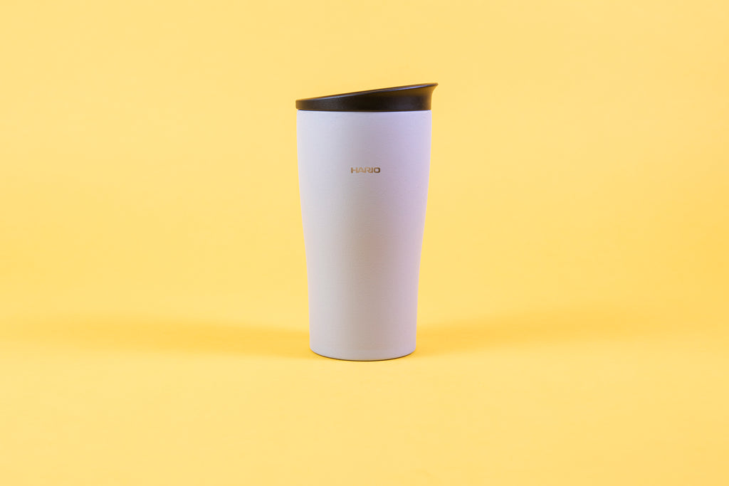Textured white coffee tumbler with Hario logo and black lid.