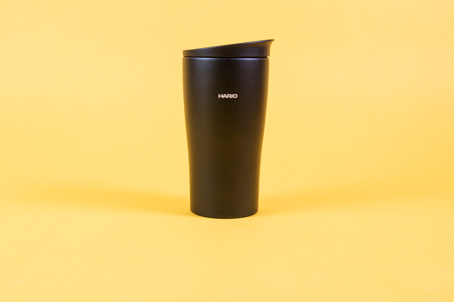 Textured black coffee tumbler with white Hario logo and black lid.