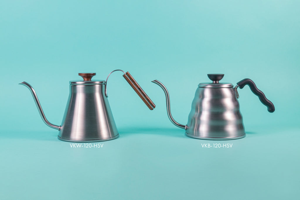 Stainless steel kettle with gooseneck spout, wood handle and flat, wood lid knob; and a stainless steel beehive shaped kettle with gooseneck spout and black plastic wavy handle and flat black plastic lid knob, set against a light blue background.