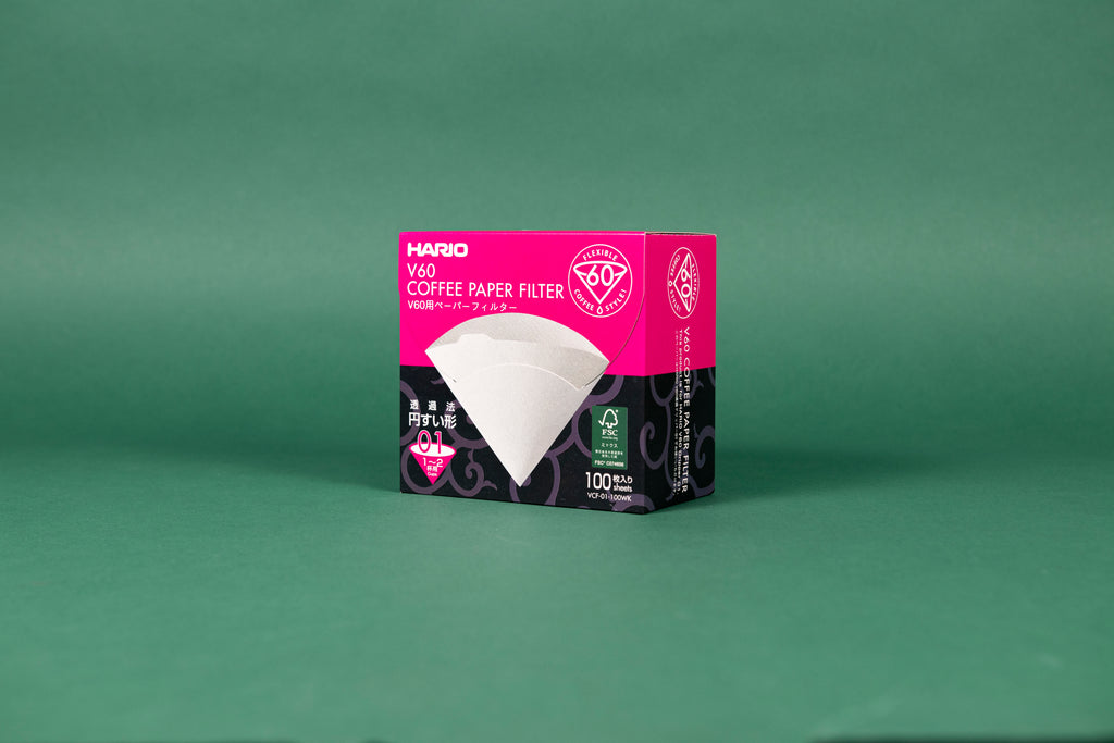 Large pink and black cardboard box with tabbed flip top lid with picture of white paper filter cone on front with white text and set against a green background.
