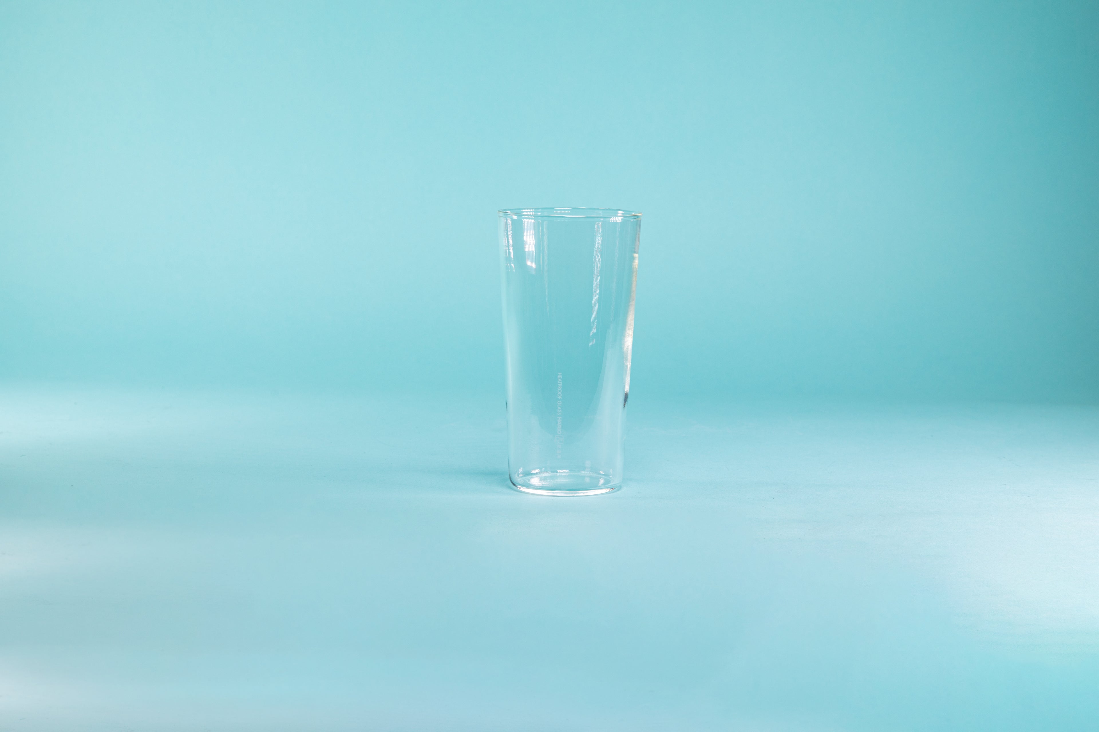 Thin, tall glass tumbler against a blue background.