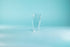 Thin, tall glass tumbler against a blue background.