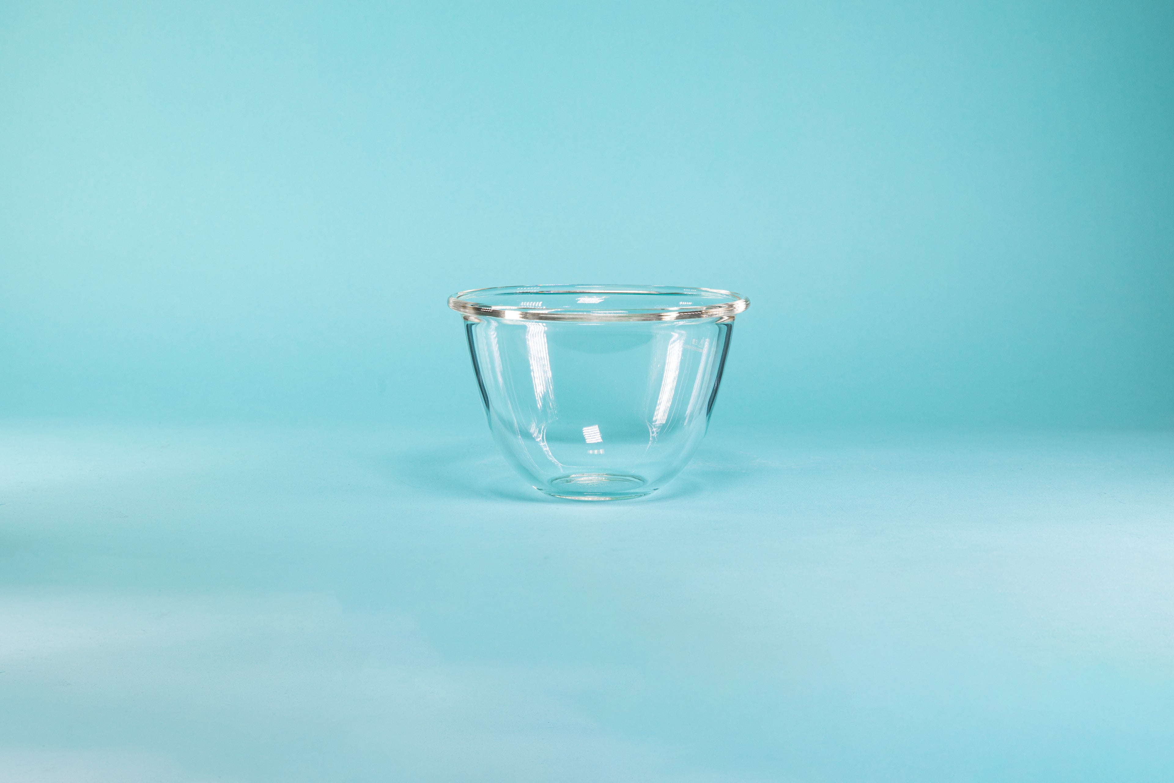 Glass mixing bowl on a blue background.