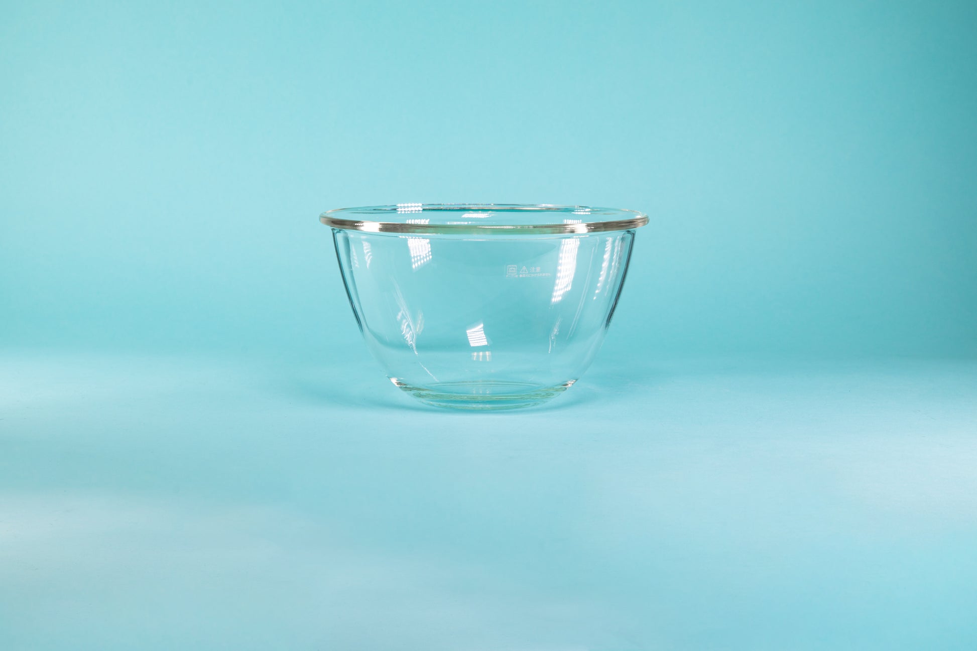 Glass mixing bowl on a blue background.