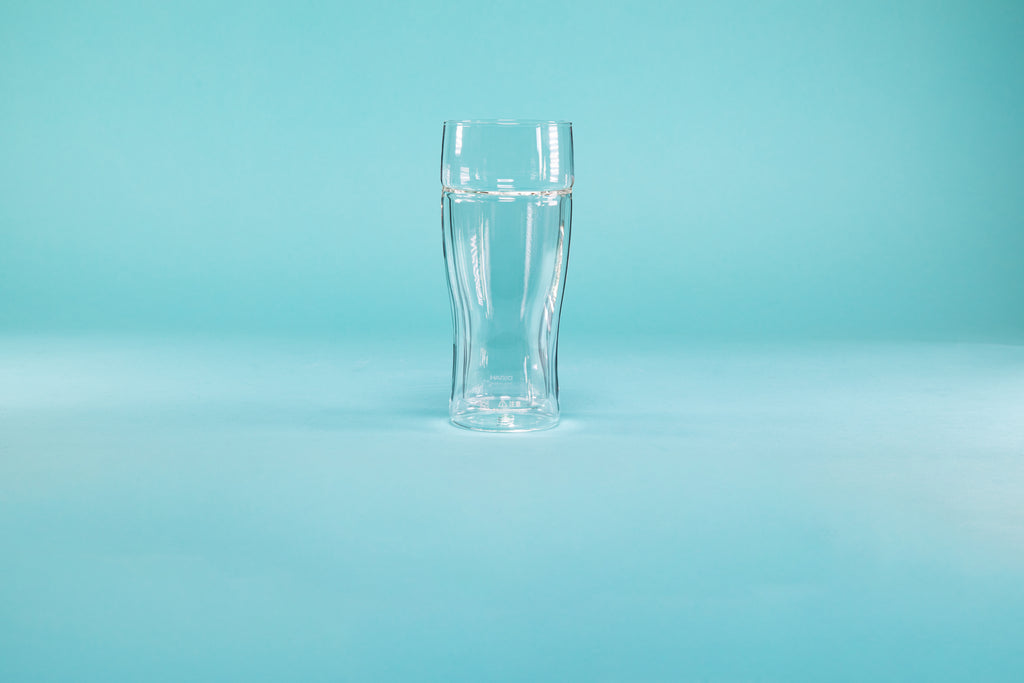 Double wall clear beer glass on a blue background.