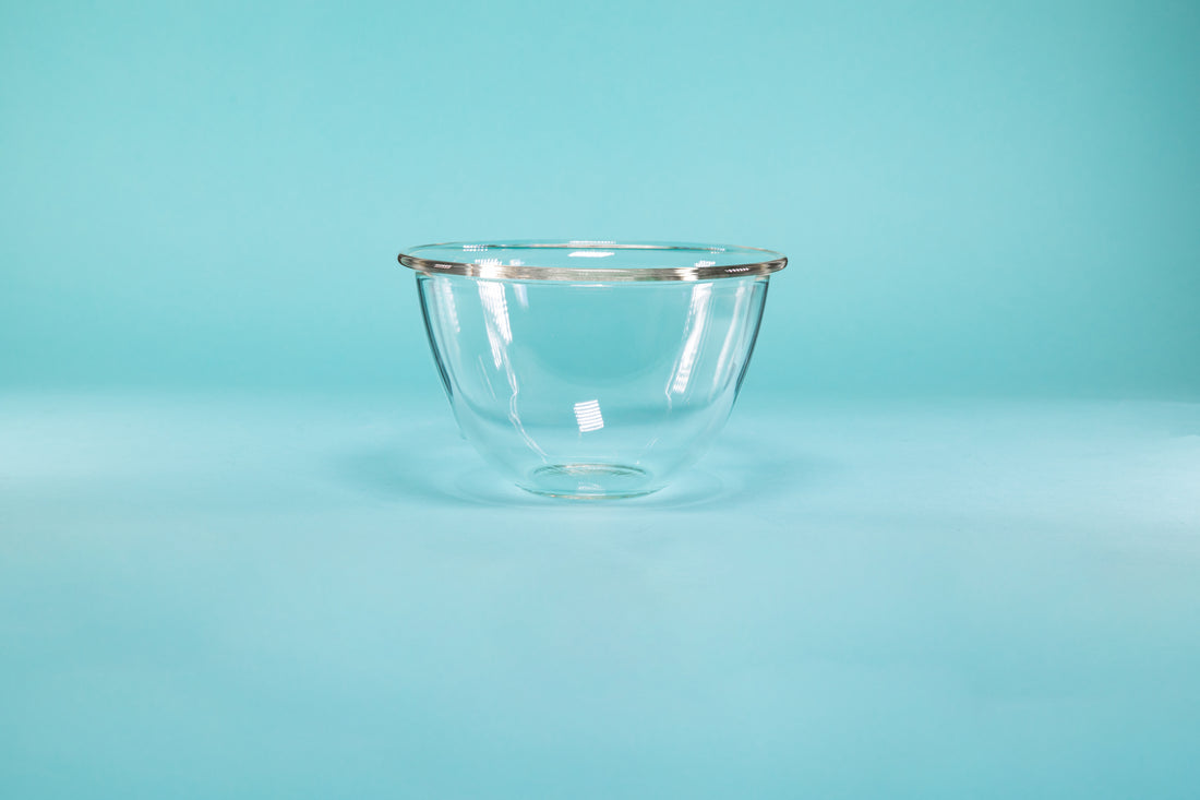 Glass mixing bowl on a blue background.