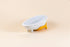 White glazed porcelain dog bowl shaped like a bathtub with mango yellow silicone non-slip mat.