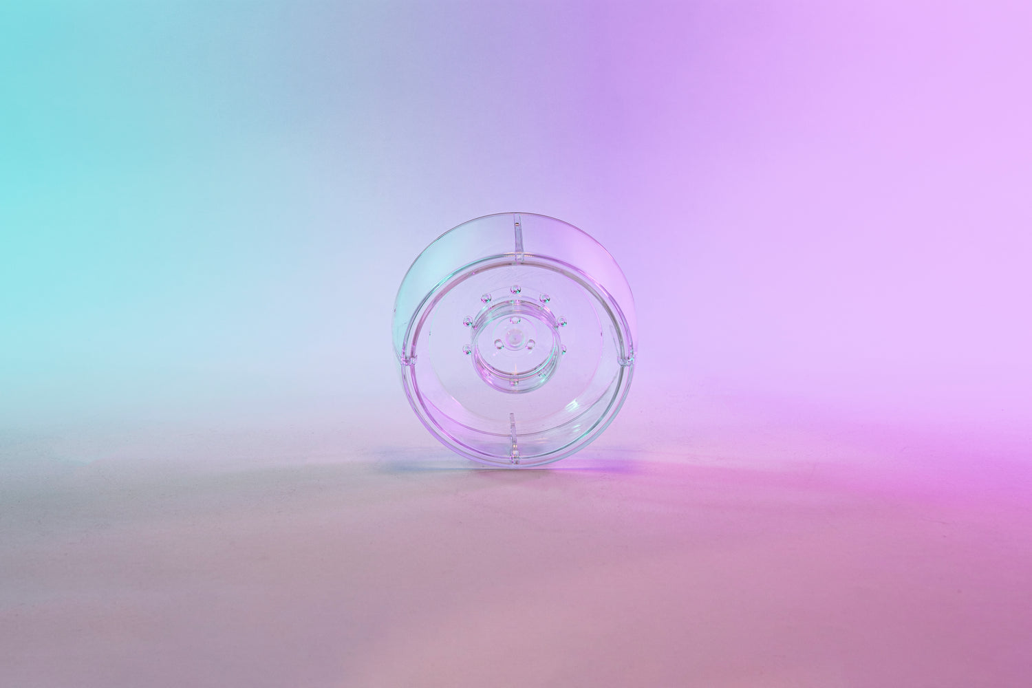 Clear plastic ring with interior smaller ring and holes for liquid to drain through. Set on a blue to purple gradient background.