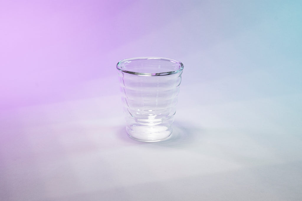 Beehive shaped round double-wall coffee glass on a purple gradient background.