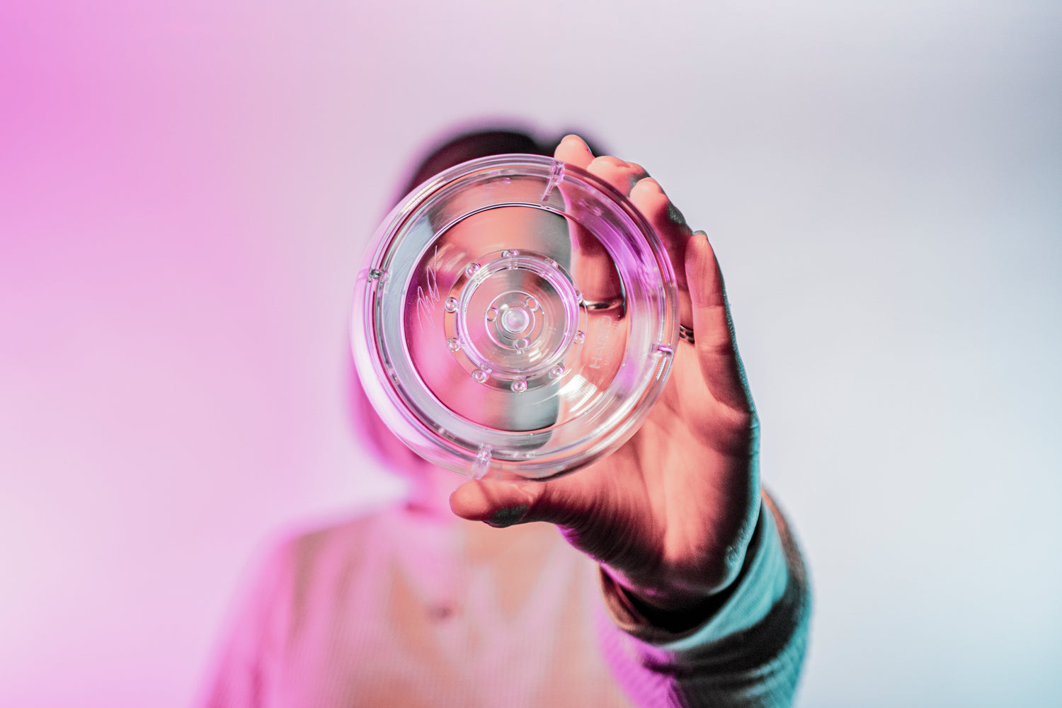 Model holding a clear plastic ring with interior smaller ring and holes for liquid to drain through.