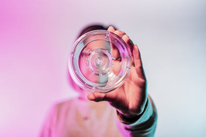 Model holding a clear plastic ring with interior smaller ring and holes for liquid to drain through.