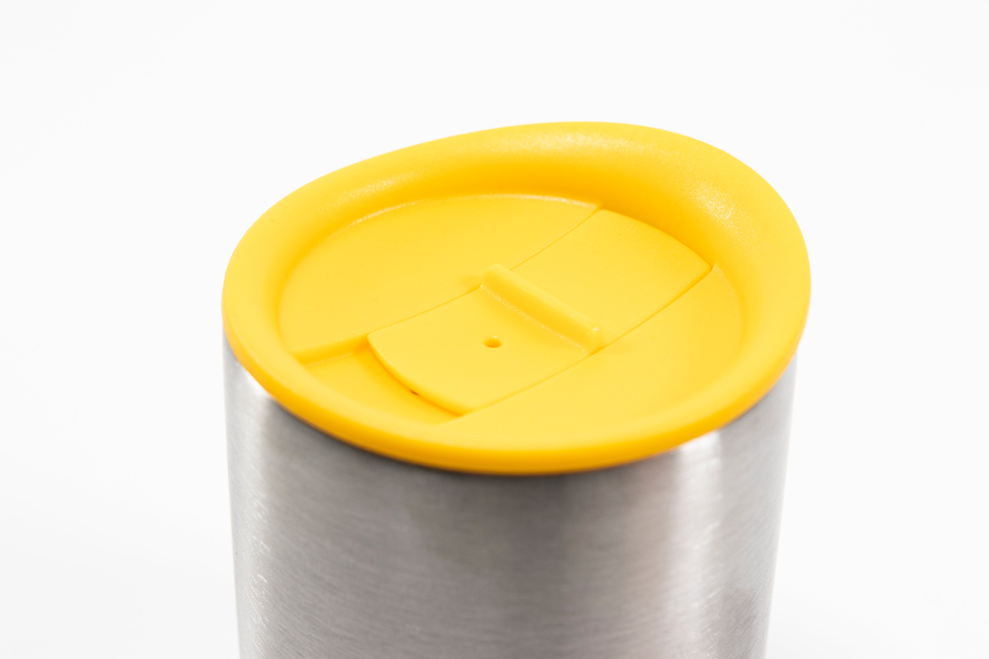 Close up of yellow silicone lid showing sliding stopper and the top of a short stainless steel insulated mug.